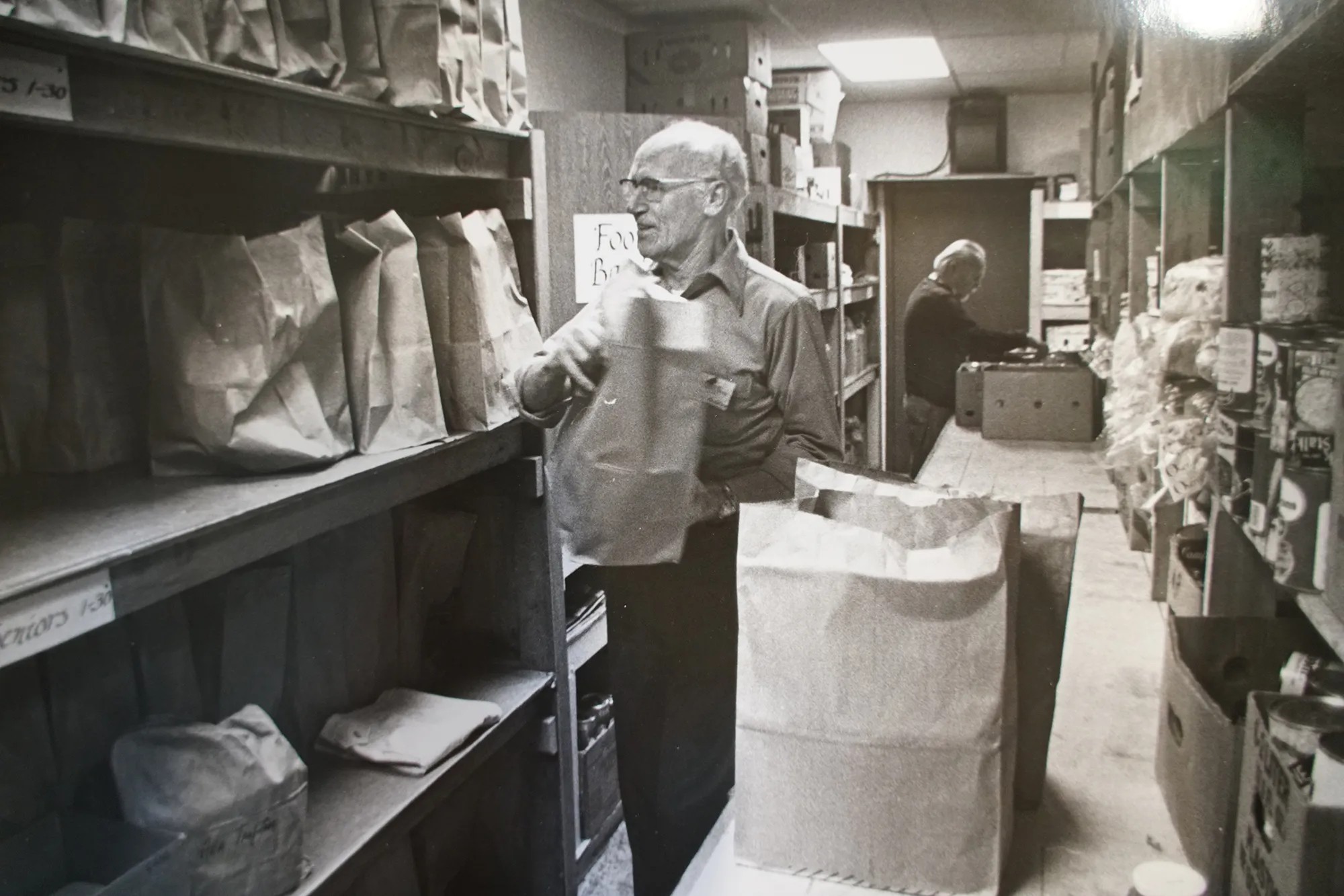 John van Hengel, black and white, stocking food bank shelves