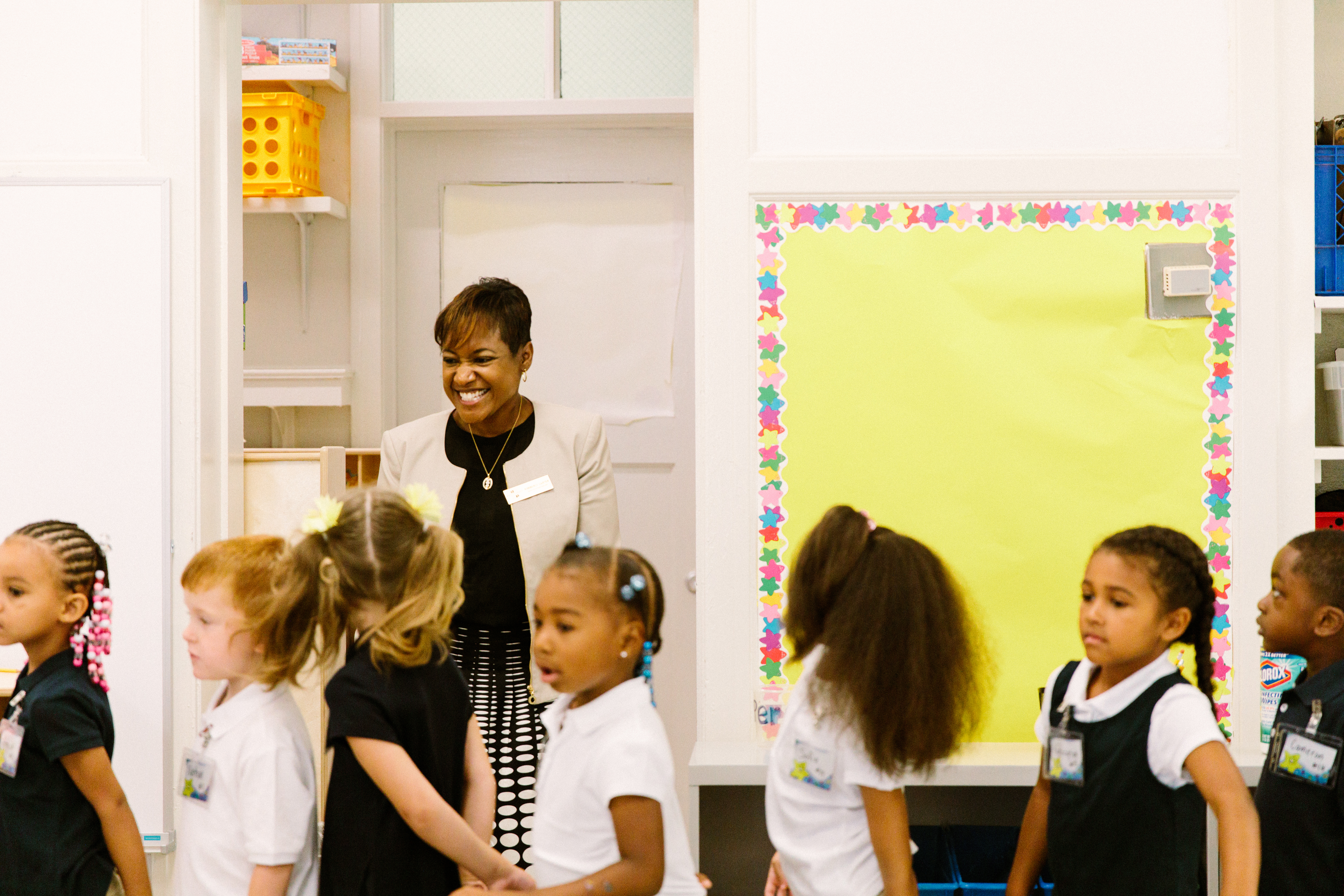 Smiling teacher, young students in a classroom