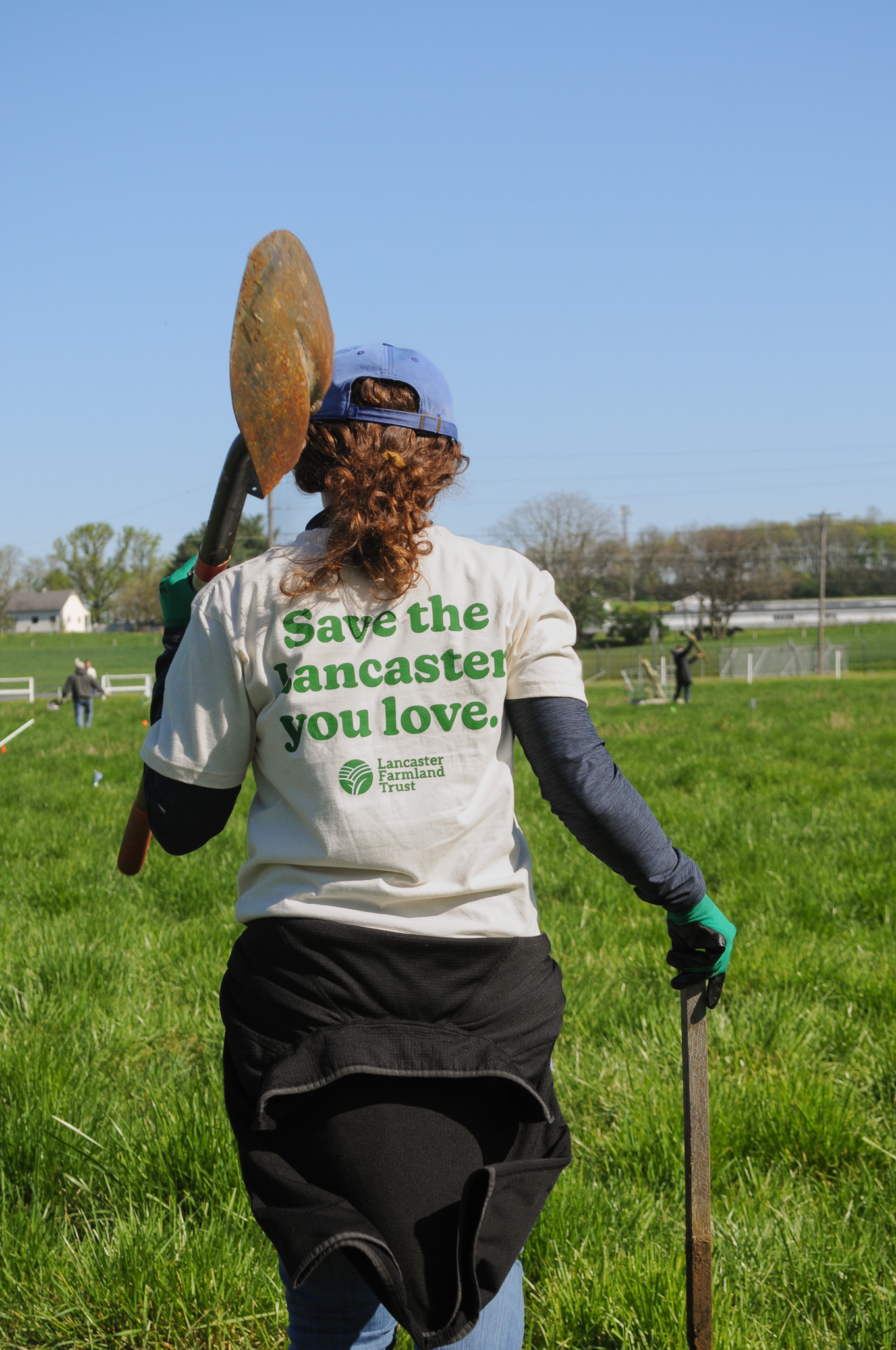 Lancaster Farm Trust, Woman walking with shovel and gardening equipment 
