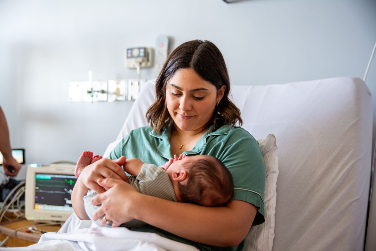 New mom holding baby in hospital bed, stock image