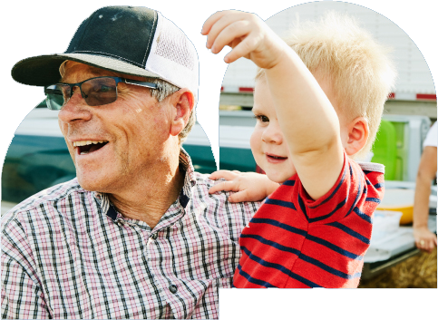 An older man wearing a hat holds a child.