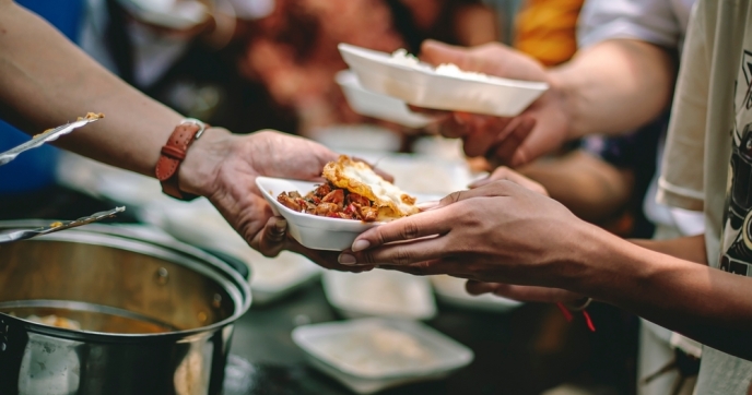 Volunteers handing out food, close up on food/hands. Credit: addkm/Shutterstock